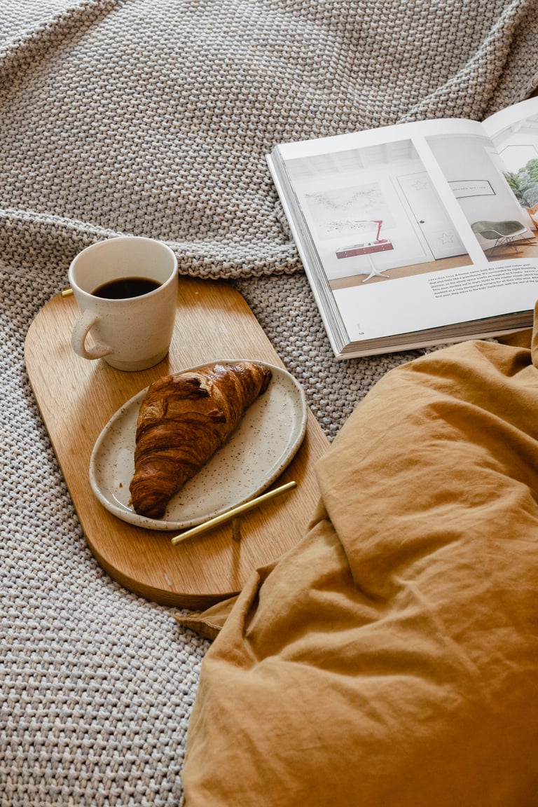 Croissant and Coffee on Wooden Tray with Magazine on Bed